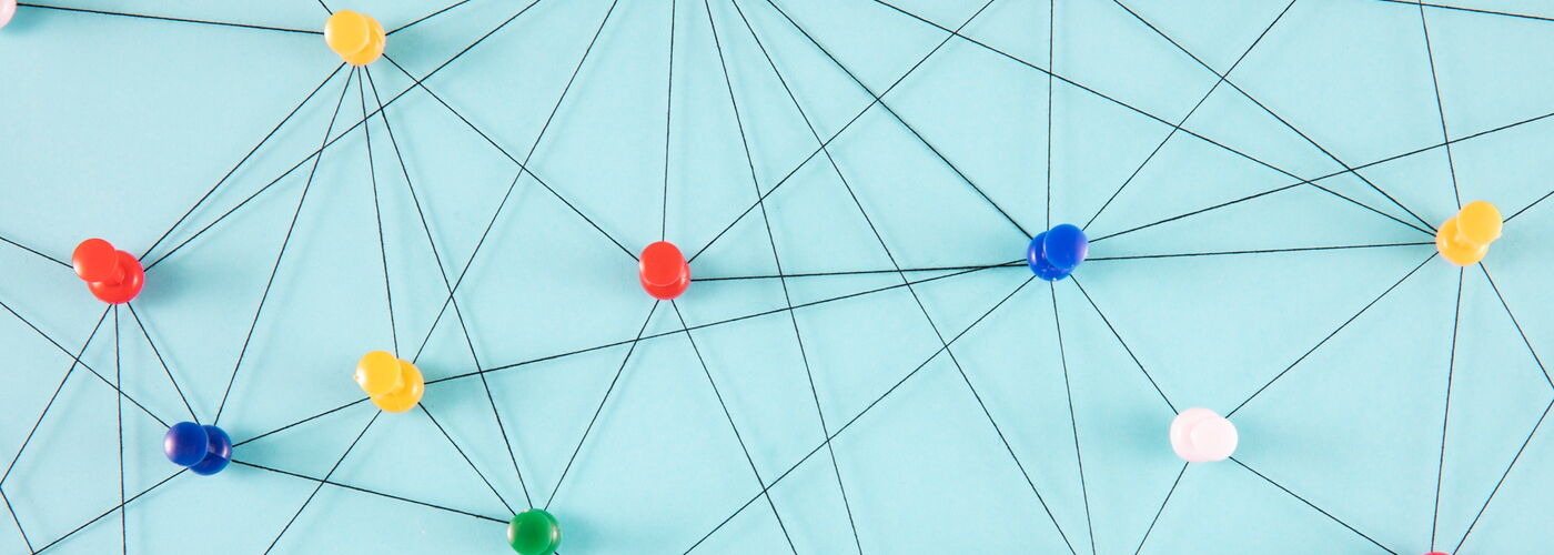 Pinnnadeln mit faden zu einem Netzwerk verbunden auf blauem Untergrund
